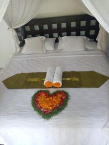 a bed with two towels and a heart made out of flowers at Ritinula Resort in Tejakula