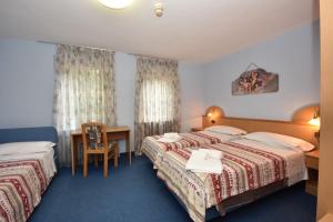 a hotel room with two beds and a desk at Hotel Villa Agomer in Canazei