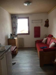 a living room with a red couch and a window at Les studios du chalet club Valfréjus in Modane