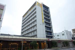 a tall white building with a sign on it at Super Hotel Miyazaki Natural Hot Springs in Miyazaki