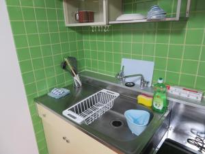 a kitchen with a sink and green tiles at 札幌市中心部大通公園まで徒歩八分観光移動に便利なロケーションe507 in Sapporo