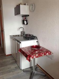 Il comprend une cuisine équipée d'un évier et d'une cuisinière avec une table. dans l'établissement Les studios du chalet club Valfréjus, à Modane