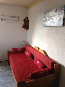 a red couch with red pillows in a room at Les studios du chalet club Valfréjus in Modane +4 photos