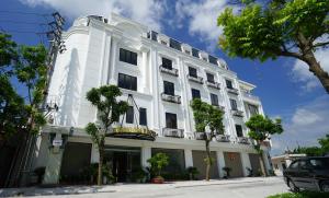 a white building with trees in front of it at Khách Sạn Hoàng Gia II in Thái Bình