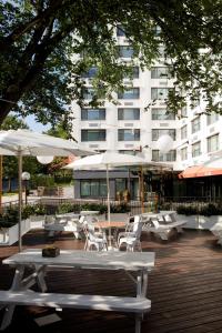 un patio con sillas blancas, mesas y sombrillas en Glover Park Hotel Georgetown, en Washington