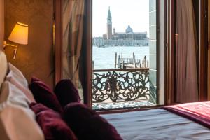 une personne qui se couche dans un lit et qui regarde l'eau par une fenêtre dans l'établissement A Tribute To Music Residenza, à Venise
