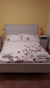 ein Bett mit einer weißen Tagesdecke mit Blumen darauf in der Unterkunft Bed and breakfast Grim in Triest