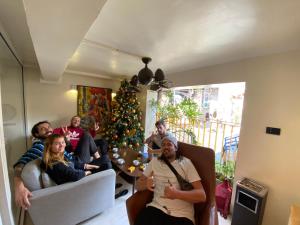 un grupo de personas sentadas en una sala de estar con un árbol de Navidad en Hanoi Banana Hostel en Hanói