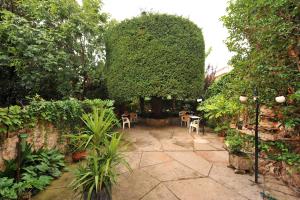 a patio with tables and chairs in a garden at Hotel Tall de Conill in Capellades