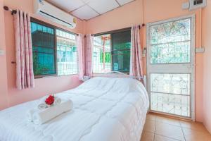 - une chambre avec un grand lit blanc et des fenêtres dans l'établissement Gaiwandhanat Homestay, à Bangkok