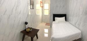 a white bedroom with a bed and a table at Arriyus Apartelle in Maya