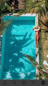 a woman in a bathing suit with a umbrella walking into a swimming pool at Vilamaré in São Miguel do Gostoso