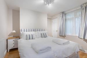 een witte slaapkamer met een groot wit bed met kussens bij Central Brighton Town House in Brighton & Hove