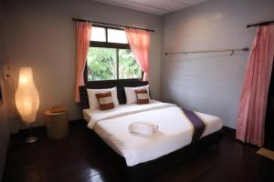 a bedroom with a large white bed with a window at Marina hut guest house in Ko Lanta