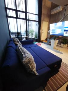 a large blue couch in a room with large windows at EkoCheras Balcony City View King Bed Rooftop Pool High Speed Fibre Internet MRT Connection in Kuala Lumpur