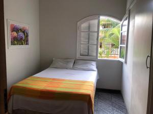 Cama en habitación con ventana en Casa Da Praia, en Cabo Frío