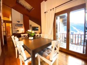 a dining room with a table and chairs and a balcony at Isards, Atico rustico con chimenea en el tarter, zona Grandvalira in El Tarter
