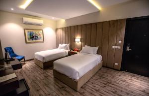 um quarto de hotel com duas camas e uma cadeira azul em Grand Ittehad Boutique Hotel em Lahore
