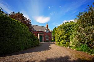 ein rotes Haus mit Hecken vor einer Einfahrt in der Unterkunft The Head Gardeners Cottage, Dunbar in Dunbar
