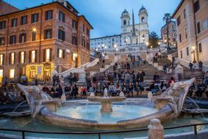 un grupo de personas sentadas alrededor de una fuente en una ciudad en Spagna Secret Rooms en Roma