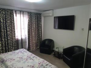a bedroom with a bed and a chair and a television at Pensiunea Andrei in Râmnicu Vâlcea