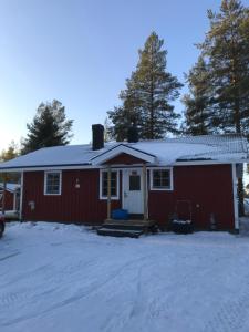 uma casa vermelha com neve em cima em Rödberget em Råneå