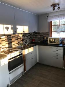 uma cozinha com armários brancos e um forno com placa de fogão em Rödberget em Råneå