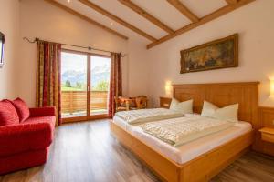 a bedroom with a bed and a red chair at Pension Noella in Sankt Johann in Tirol