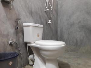 a white toilet in a bathroom with a shower at Induwara Guest in Ella