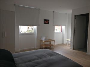 een slaapkamer met witte muren, 2 ramen en een bed bij Casa Irene in Aveiro