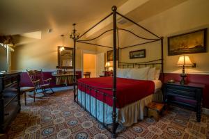 Steele Mansion Inn & Gathering Hub في Painesville: غرفة نوم مع سرير مظلة مع بطانية حمراء