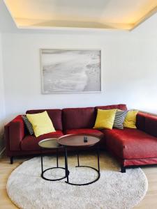 サン・セバスティアン・デ・ラ・ゴメラにあるHauzify I Apartamento Ruiz de Padronのリビングルーム(赤いソファ、テーブル2台付)