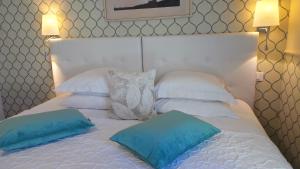 a white bed with two blue pillows on it at Hotel Relais Du Postillon in Antibes