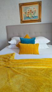 a large white bed with yellow pillows and a painting at Hotel Relais Du Postillon in Antibes