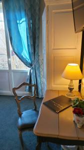 a chair and a desk with a laptop and a lamp at Hotel Relais Du Postillon in Antibes