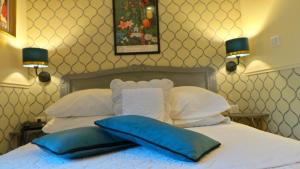 a bed with two blue pillows on top of it at Hotel Relais Du Postillon in Antibes