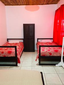 1 dormitorio con 2 camas con sábanas rojas y armario en Zurisadai, en Puerto Ayora