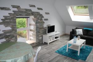 sala de estar con sofá, mesa y TV en Le petit Kichon en Gérardmer