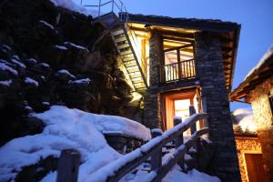 een huis in de sneeuw met het licht aan bij Case Gran Paradiso di Charme Villaggio La Barmaz in Rhemes-Saint-Georges