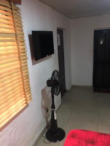 a room with a fan and a tv on a wall at DE’ BAKERS SUITES in Lagos