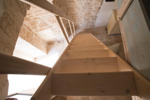 a wooden staircase in a room with a stone wall at Trullidea in Alberobello