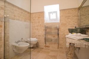 a bathroom with a toilet, sink and tub at Trullidea in Alberobello