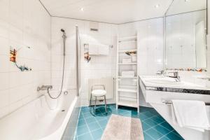 La salle de bains est pourvue d'une baignoire, d'un lavabo et d'une douche. dans l'établissement Haus Capricorn - Appartement Mountain View, à Gargellen