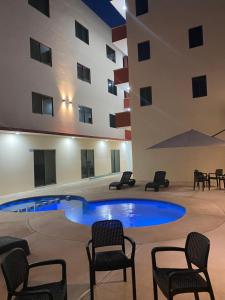 een zwembad in het midden van een gebouw met stoelen bij Hotel Ambra in Playa del Carmen
