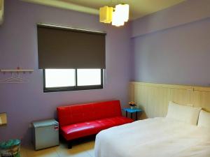 馬公市的住宿－岑之堡民宿，一间卧室配有红色的床和红色的沙发