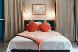 a bed with orange pillows in a room at Le Jardin de Corail, Magnifique F1 tout juste rénové, à 2 pas du lagon de la Saline les Bains in La Saline les Bains