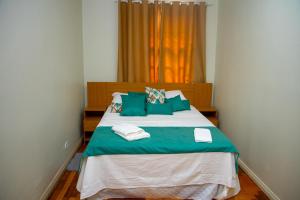 a bedroom with a bed with green and white pillows at Hotel Casa Branca in Uruguaiana