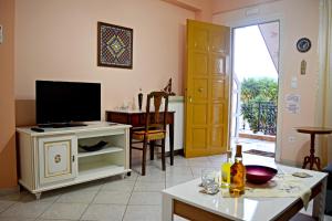 a living room with a television on a cabinet and a door at Korona Apartments in Vathi