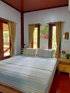 a bedroom with a large white bed with windows at Baan Moonchan House in Chaloklum