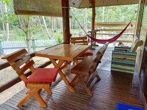 einen Holztisch und Stühle auf einer Veranda mit einer Hängematte in der Unterkunft Baan Moonchan House in Chaloklum